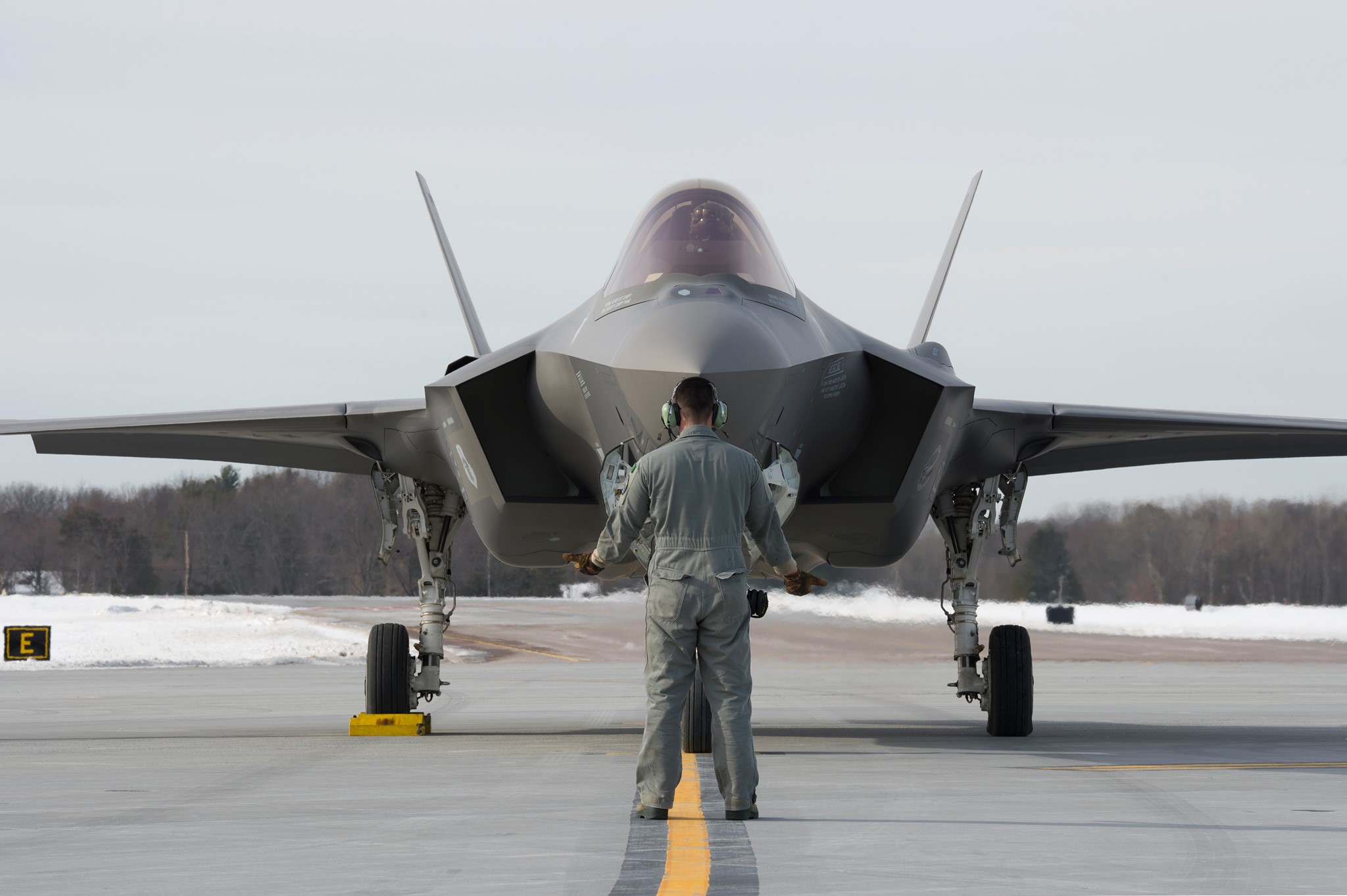 A crew chief marshals an F-35 on the flight line